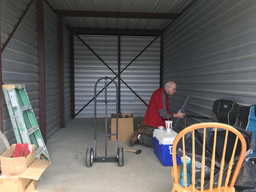 Mostly empty storage unit with one man in view